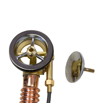 Close-up of a walk-in tub brass and chrome drain assembly with copper pipe overflow plate and stopper components