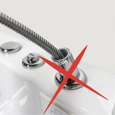 Red X over a chrome hand shower hose barrel connector on a walk-in tub deck showing an incorrect or faulty installation