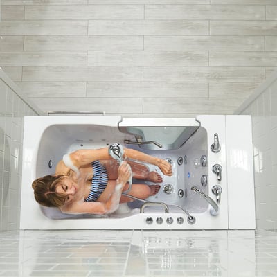 Woman relaxing with eyes closed in the Ella Ultra walk-in tub, holding a handheld shower wand surrounded by bubbles and jets