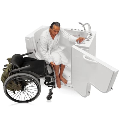 Wheelchair user in white robe transferring into an Ella 30x52 wheelchair accessible walk-in tub with open door panel