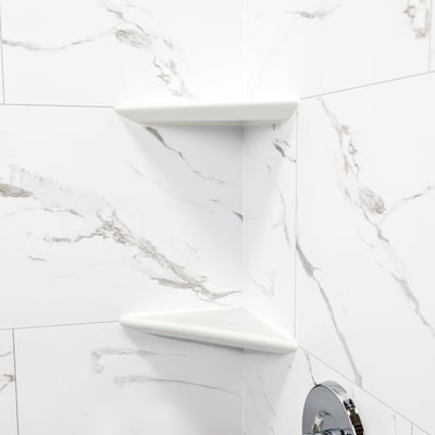 Two white corner shower shelves mounted on marble-look wall panels inside an Ella's Bubbles accessible shower stall