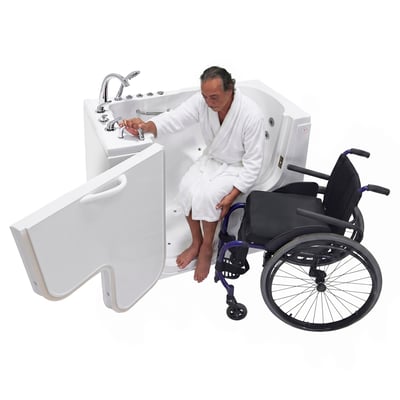 Side view of a man in a white robe seated at the open door of an Ella walk in tub beside a wheelchair