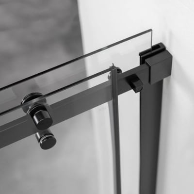 Gros plan de la quincaillerie de porte coulissante noir mat et du panneau en verre trempé sur une douche à l’italienne Ella Primo