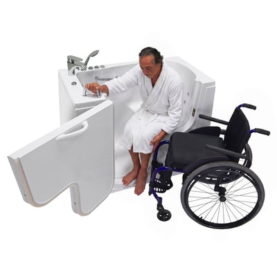 Man in a white robe seated on the transfer ledge of a walk-in tub, wheelchair parked to his right