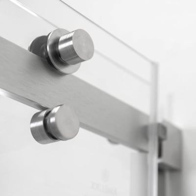 Gros plan de la quincaillerie de porte coulissante en acier inoxydable brossé et des boutons cylindriques sur une porte de douche en verre trempé Primo