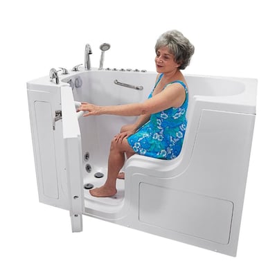 Senior woman seated in the Ella Transfer60 wheelchair accessible walk-in bathtub closing the outward swing door with hydro jets visible