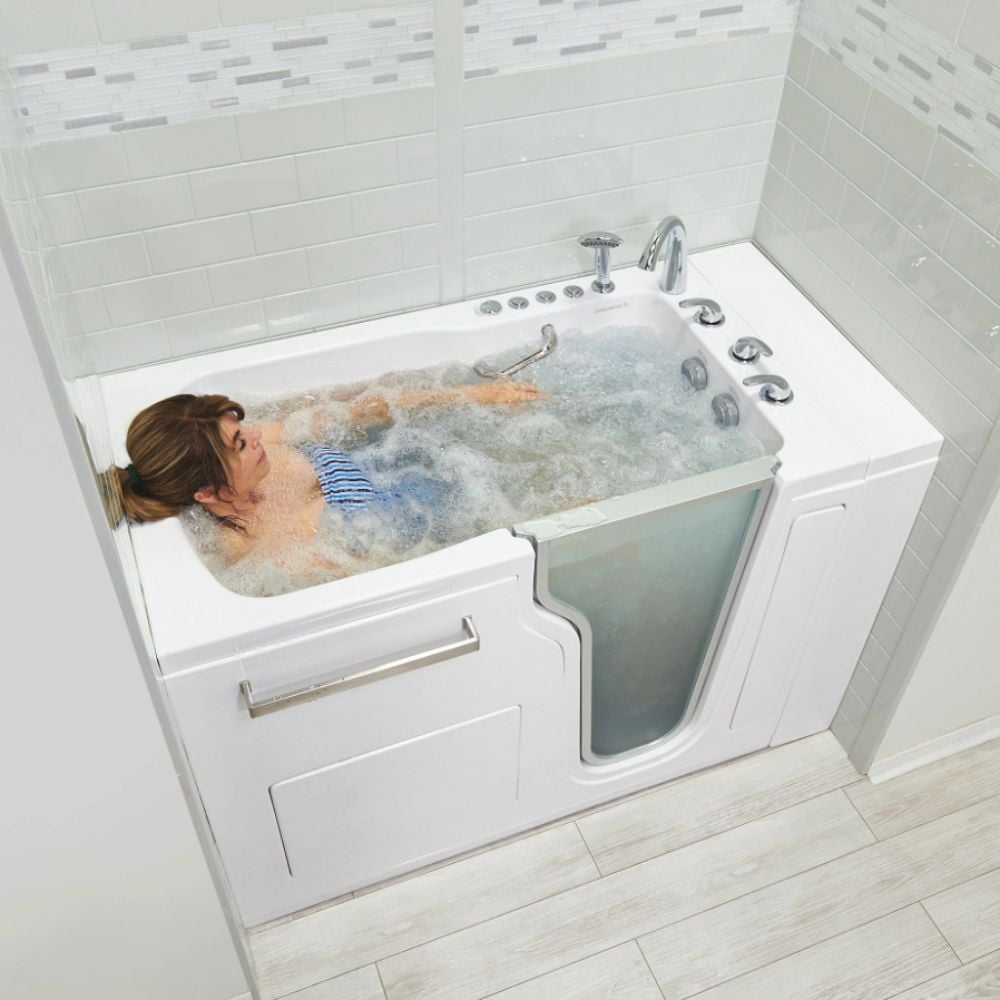 Woman relaxing in bubbly hydro massage jets inside an Ella Ultra acrylic walk-in tub with glass door panel