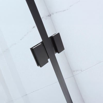 Primer plano de la abrazadera de cristal en negro mate de la mampara de bañera plegable sin perfilería Ella Tidy sobre pared de azulejos de mármol