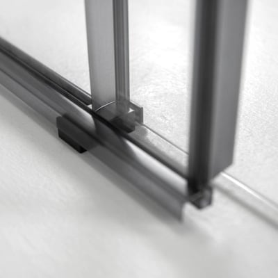 Gros plan du rail inférieur et du cadre de la porte de douche coulissante Primo avec panneaux en verre trempé de 6 mm sur sol carrelé