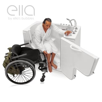 Wheelchair user in white robe transferring into the Ella Transfer 30 walk-in tub with open outward-swing door