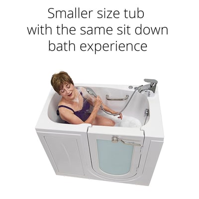 Senior woman seated in the Ella Mobile compact walk-in tub using a handheld shower sprayer with bubble bath water