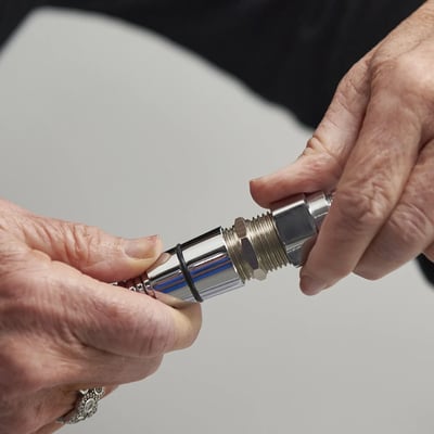 Close-up of senior hands connecting a chrome threaded hose coupling fitting for a walk-in tub or accessible shower installation