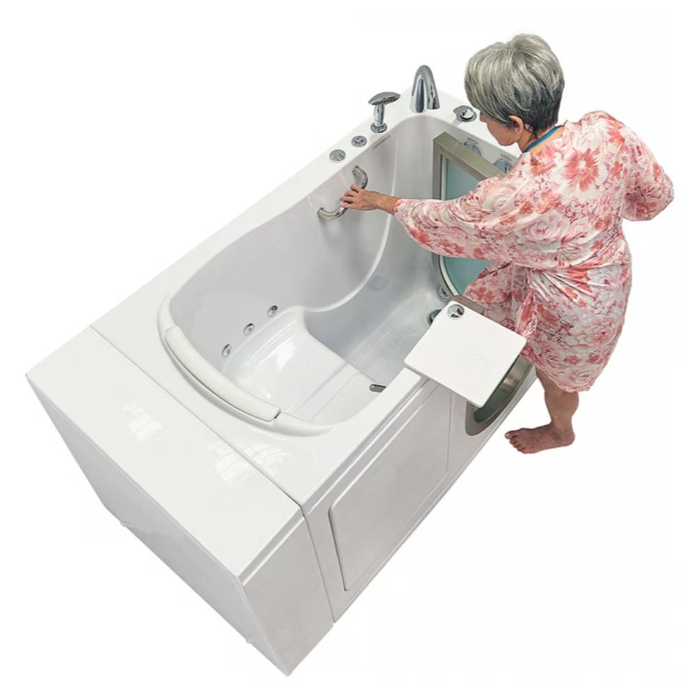 Senior woman in floral robe gripping grab bar while entering the Ella Royal acrylic walk-in tub with open side door and built-in seat