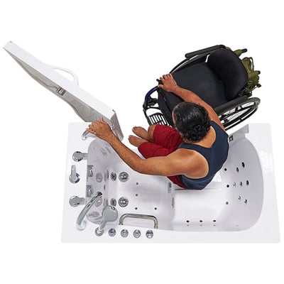 Wheelchair user transferring sideways into the Ella Transfer60 walk-in tub through the wide outward swing door from a wheelchair