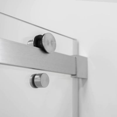 Gros plan de la quincaillerie et du rail de porte coulissante en acier inoxydable sur un panneau de porte de douche coulissante en verre trempé Primo