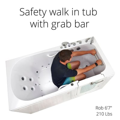 Tall man sitting inside Ella's Shak walk-in tub gripping the front grab bar, showing spacious 36x72 inch interior with hydro jets