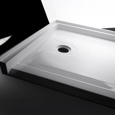 Gros plan du sol du receveur de douche accessible en fauteuil roulant en acrylique Ella avec texture antidérapante et évacuation centrale
