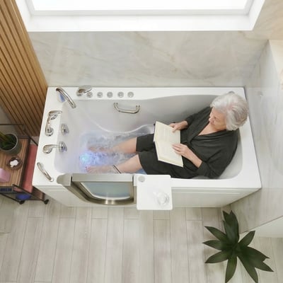 Senior woman relaxing and reading a book during a hydro massage soak in the Ella Ultimate walk-in tub with chromotherapy jets