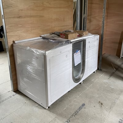 Bañera con puerta Ella envuelta en embalaje de plástico protector con accesorios encima, lista para la entrega e instalación
