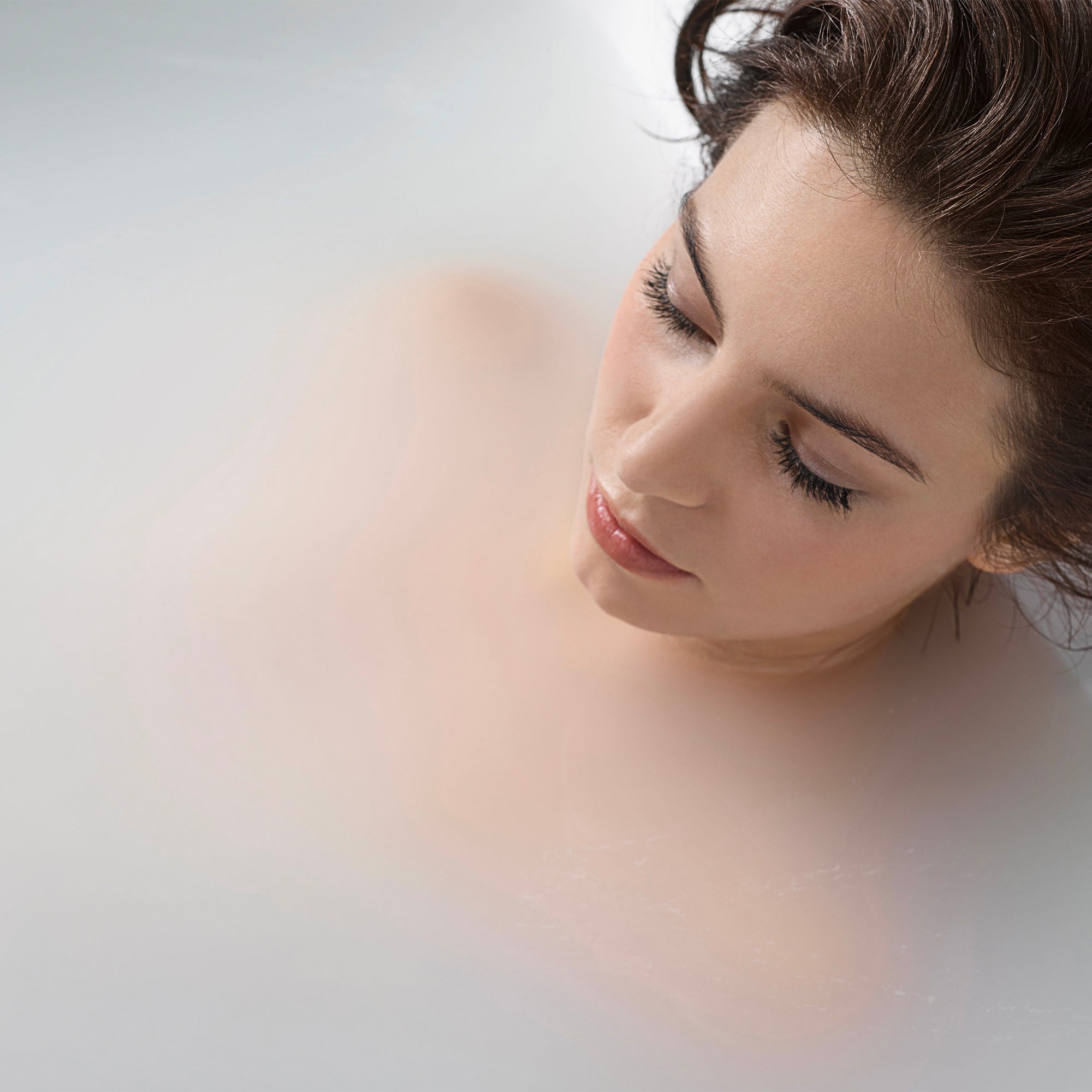Woman relaxing in an Ella walk-in tub filled with milky white microbubble therapy water