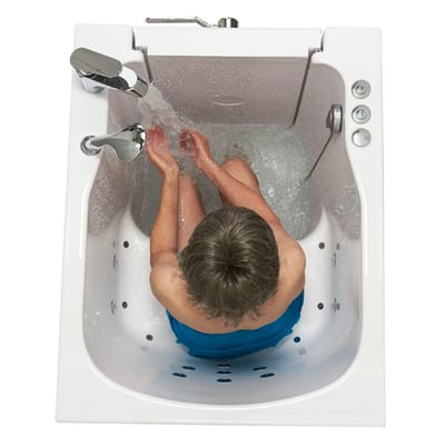 Overhead view of senior bathing in Ella front entry walk-in tub with hydro jets, faucet running, and outward swing door open