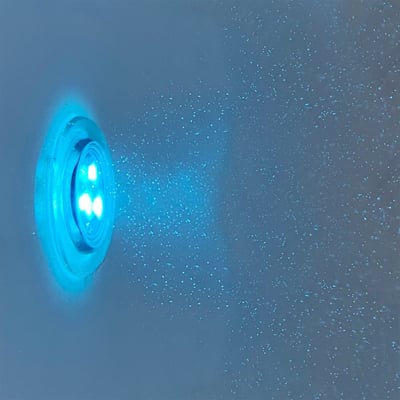 Close-up of a glowing blue LED chromotherapy light mounted inside an Ella walk-in tub with water droplets