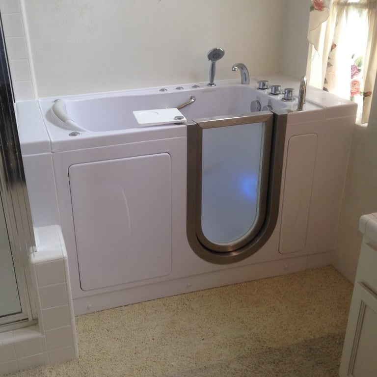 White Ella walk-in tub with stainless steel door frame, hydrotherapy jets, handheld showerhead, and chrome controls installed in a home bathroom