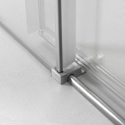 Primer plano del carril inferior cromado y el soporte de esquina en la puerta de ducha corredera de vidrio templado Ella Primo