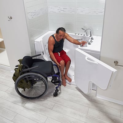 Person transferring from his chair into the Ella Transfer30 walk-in tub with open door and jetted interior