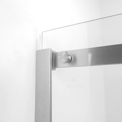 Primer plano de los herrajes de acero inoxidable cepillado y el panel de vidrio templado en la puerta de ducha corredera Amluxx Primo
