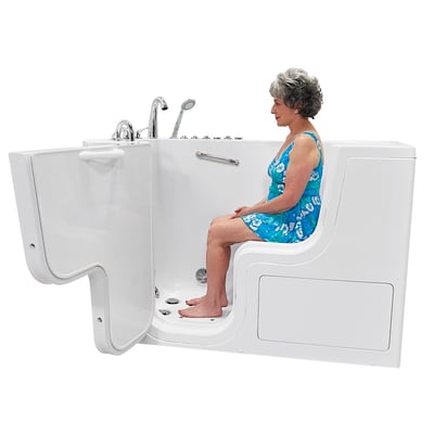 Senior woman in a floral dress seated inside the Ella Transfer60 wheelchair accessible walk-in tub with outward swing door open