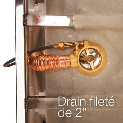 Gros plan d’un drain fileté de 2 pouces en laiton avec serpentin en cuivre installé sous une baignoire à porte Ella