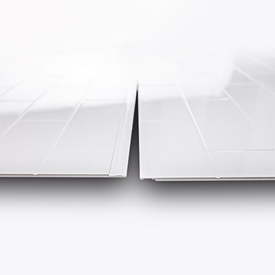 Close-up of two white glossy subway tile-patterned shower wall panels showing interlocking edges and layered profile