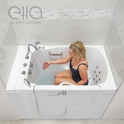 Woman seated in an Ella walk-in tub testing warm water flow from the faucet with hydro jets and grab bars visible