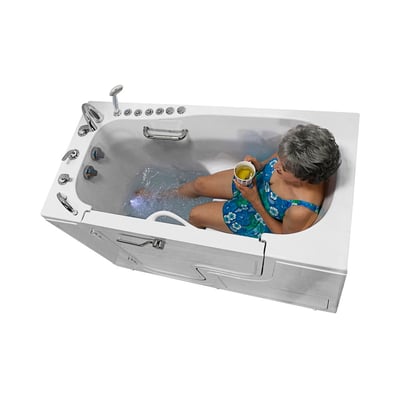 Senior woman in a floral swimsuit holding a warm drink while relaxing in an Ella Transfer60 walk-in tub with hydro jets active