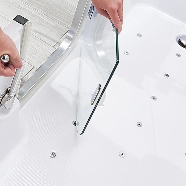 Person opening the clear tempered glass door of the Ella Acrylic Laydown72 walk-in tub showing jet nozzles inside