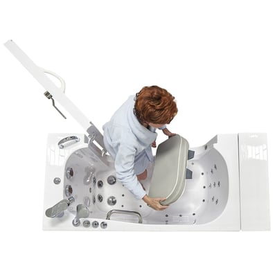 Senior woman placing a seat riser cushion inside an Ella walk-in tub with hydro massage jets and chrome fixtures