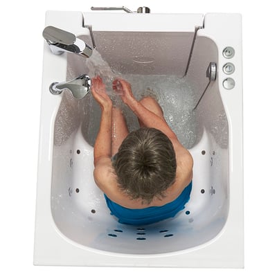 Vue de dessus d’une personne âgée prenant un bain dans une baignoire à porte Ella à entrée frontale, avec l’eau coulant du robinet chromé et les jets d’hydrothérapie visibles