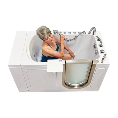 Senior woman in a blue swimsuit using a handheld showerhead while seated inside the Ella Elite walk-in tub 30x52