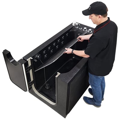 Ella's Bubbles technician installing a seat inside a black microbubble therapy pet spa walk-in tub with open door and jets