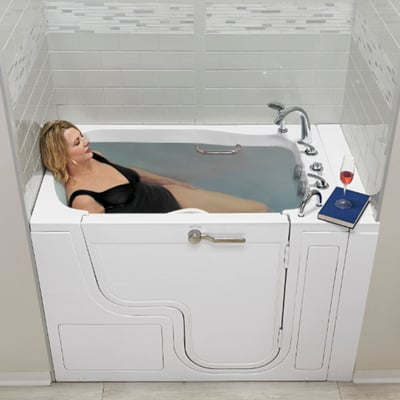 Woman relaxing in the Ella Transfer XXL wide-door walk-in tub with a book and wine glass on the ledge
