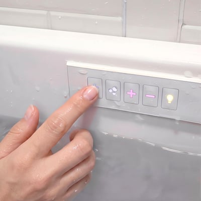 Finger pressing the digital control pad on an Ella's Bubbles walk-in tub with jet, light and drain buttons