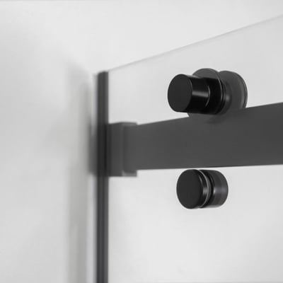 Primer plano de los herrajes de la puerta corredera en negro mate y el mecanismo de rodillos en la puerta corredera de ducha de vidrio templado Primo