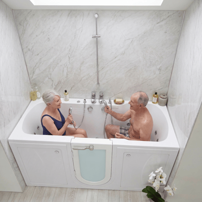 Senior couple sitting together and chatting in the Ella Big4Two two-seat walk-in tub with outswing door and handheld showers