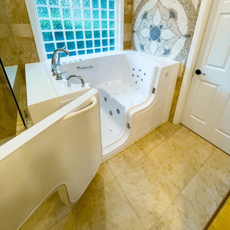 White Ella walk-in tub with open door showing hydrotherapy jets and built-in seat in a marble tile bathroom