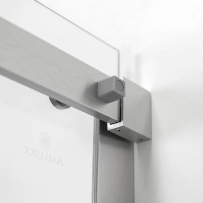 Gros plan du rail supérieur en acier inoxydable brossé et du support mural sur la porte de douche coulissante en verre trempé Ella Primo