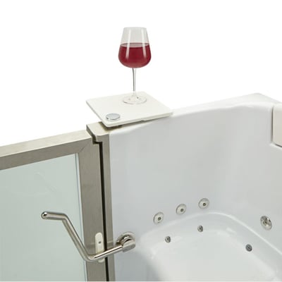 Close-up of a walk-in tub swivel tray holding a red wine glass beside the stainless steel door frame and hydro jets