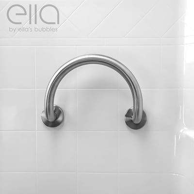Primer plano de barra de apoyo semicircular de acero inoxidable cepillado de Ella's Bubbles montada en pared de baño con azulejo blanco