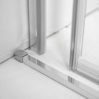 Primer plano de soporte de esquina cromado y umbral de perfil bajo en una puerta de ducha corredera de cristal templado de 8 mm
