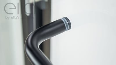 Gros plan d’une poignée de barre d’appui courbée noir mat sur le cadre de la porte de douche coulissante encadrée Ella Duo